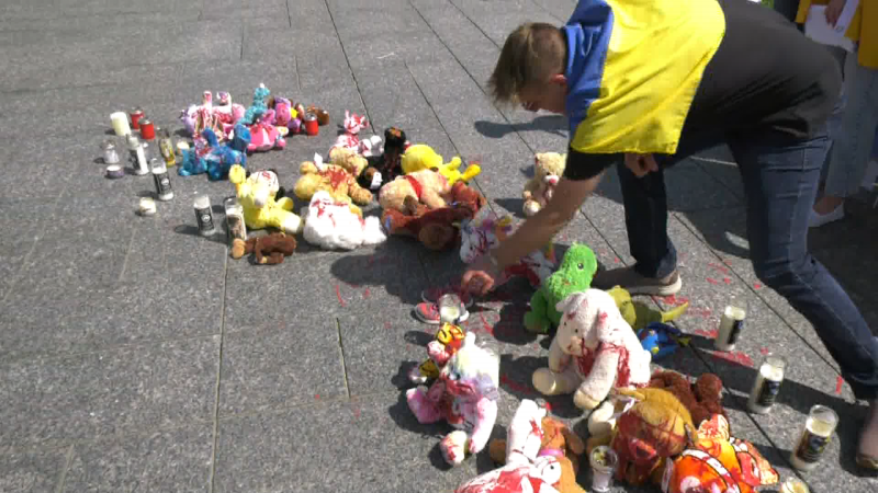 A demonstrator places a small pair of shoes down at a temporary monument dedicated to children impacted by the war in Ukraine. (Galan McDougall/CTV News Edmonton)