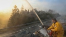 Northfield fire department member Seth Slauenwhite sprays down a flare up along highway 103 near Shelburne, Nova Scotia, N.S. in this Saturday, June 3, 2023 handout photo. (Communications Nova Scotia)