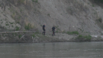 Police officers walk the bank of the North Saskatchewan River in Edmonton on June 4, 2023, in search for a 14-year-old swimmer who got swept away in a current near Terwillegar Park. 