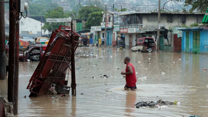 A man wades through a street flooded after a heavy rain in Port-au-Prince, Haiti, Saturday, June 3, 2023. (AP Photo/Odelyn Joseph)
