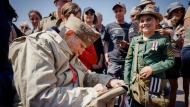A U.S. veteran signs the bag of a World War II enthusiasts during a gathering in preparation of the 79th D-Day anniversary in Sainte Marie Elise, Normandy, France, Sunday, June 4, 2023. The landings on the coast of Normandy 79 years ago by U.S. and British troops took place on June 6, 1944. (AP Photo/Thomas Padilla)
