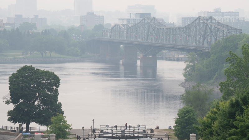 A person walks across the Rideau canal gates where it meets the Ottawa river, in Ottawa, Monday, June 5, 2023. (Adrian Wyld/THE CANADIAN PRESS)