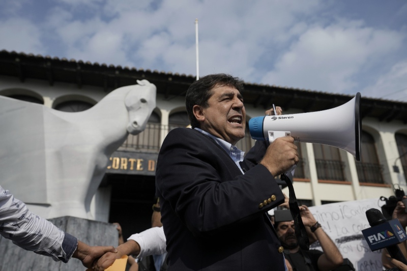 FILE - Presidential candidate Carlos Pineda of the Prosperidad Ciudadana party speaks into a bullhorn after arriving at the Constitutional Court in Guatemala City on Saturday, May 20, 2023. Pineda has sent an "open letter" video to El Salvador´s President Nayib Bukele praising many of the president's most controversial measures. (AP Photo/Moises Castillo, File)