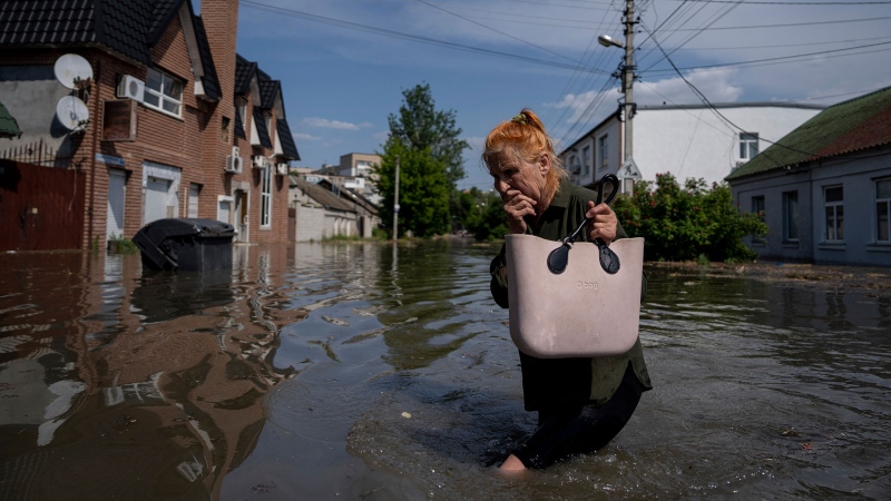 A local resident makes her way through a flooded road after the Russian troops blew the Kakhovka dam overnight, in Kherson, Ukraine, Tuesday, June 6, 2023. (AP Photo/Evgeniy Maloletka)