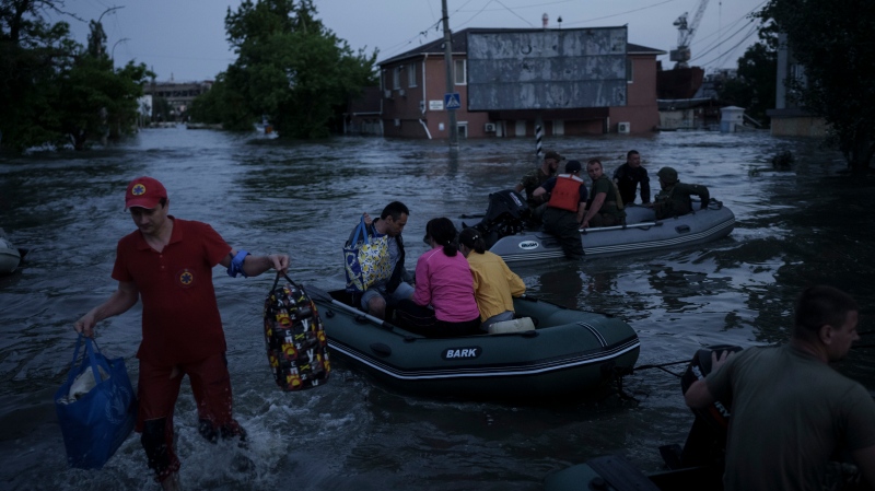 An emergency worker carries belongings of residents being evacuated from a flooded neighbourhood in Kherson, Ukraine, Tuesday, June 6, 2023. (AP Photo/Felipe Dana) 