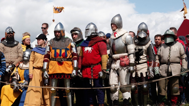 People dressed with Medieval garbs wait to see a reenactment of a tournament of knights fight, in Agincourt, northern France, Saturday, July 25, 2015. (AP Photo/Thibault Camus)