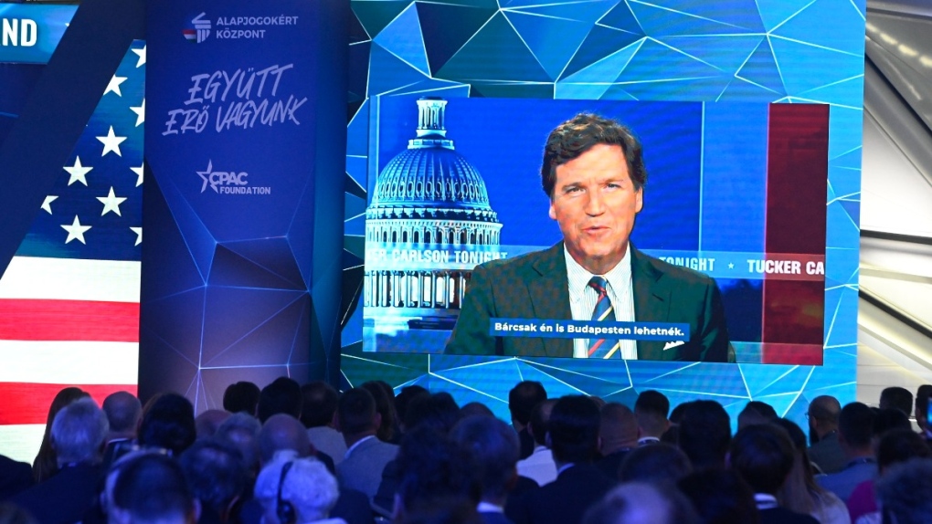Tucker Carlson appears on screen in Budapest