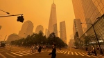 Pedestrians pass the One World Trade Center, centre, amidst a smokey haze from wildfires in Quebec and Ontario, Wednesday, June 7, 2023 in New York. (AP Photo/Julie Jacobson)