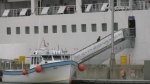 A fishing boat tied to dock near cruise ship 