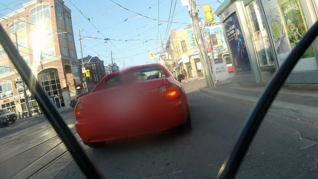 A driver of a red vehicle is seen on video cutting off a cyclist and yelling homophobic slurs. 