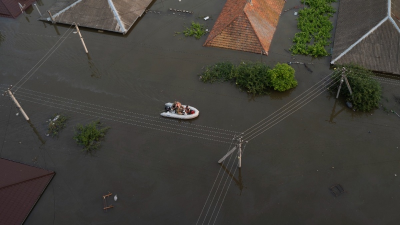 People ride on a rubber boat in a flooded neighbourhood in Kherson, Ukraine, on June 7, 2023. (Roman Hrytsyna / AP) 