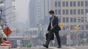 A man walks to work wearing a mask near Parliament Hill, Wednesday, June 7, 2023 in Ottawa. (THE CANADIAN PRESS/Adrian Wyld)
