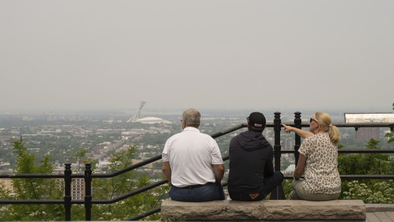 A group of tourists look east from a lookout on Mount Royal on Monday, June 5, 2023. A smog warning is in effect for Montreal and multiple regions of the province due to forest fires. THE CANADIAN PRESS/Christinne Muschi
