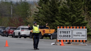A police officer directs traffic at a roadblock outside the evacuated zone of the wildfire burning in Tantallon, N.S., outside of Halifax on Monday, May 29, 2023. THE CANADIAN PRESS/Darren Calabrese