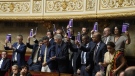 Members of the centrist opposition LIOT group hold copies of the French Constitution at the National Assembly, Thursday, June 8, 2023 in Paris. French lawmakers are debating an opposition bill which aims to return the retirement age to 62 — it went up to 64 with Macron's unpopular reform. Legislators from centrist opposition group LIOT proposed the text, supported by leftists and the far-right. (AP Photo/Lewis Joly)