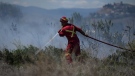 A firefighter directs water on a grass fire burning on an acreage behind a residential property in Kamloops, B.C., Monday, June 5, 2023. (THE CANADIAN PRESS/Darryl Dyck)