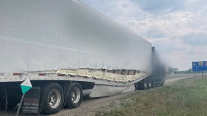 A transport truck pulled over on Hwy. 401, with damage on its right side, after a crash involving a Ontario Ministry of Transportation vehicle on June 9, 2023. (Submitted/OPP)