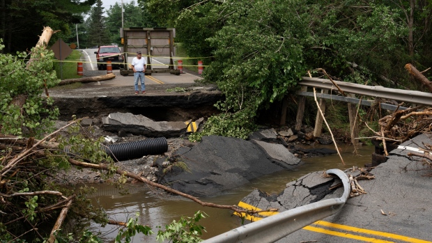 A motorist stops to survey the damage to a washed-out bridge following a major rain event near Newport Corner, N.S. on Sunday, July 23, 2023. A long procession of intense thunderstorms dumped record amounts of rain across a wide swath of Nova Scotia, causing flash flooding, road washouts and power outages. THE CANADIAN PRESS/Darren Calabrese