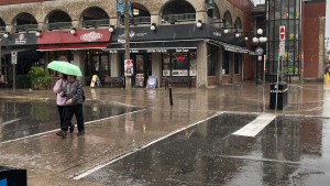 Two people share an umbrella on York Street in Ottawa's ByWard Market. Aug. 7, 2023. (Ted Raymond/CTV News Ottawa)