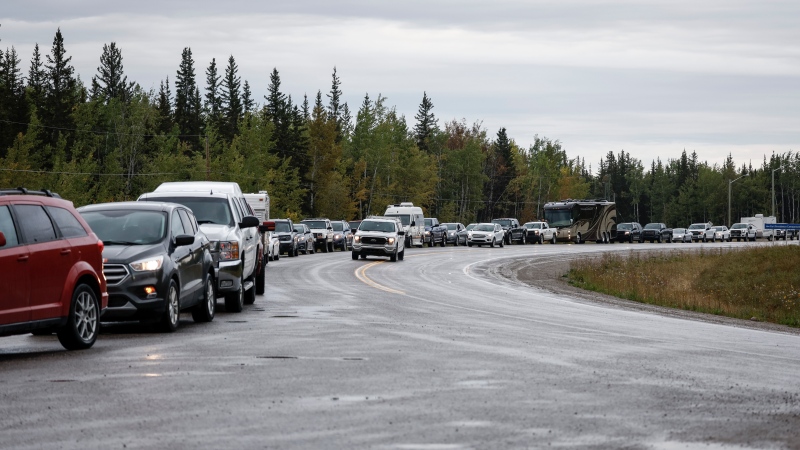 Vehicles line-up for fuel at Fort Providence, N.W.T., on the only road south from Yellowknife, Thursday, Aug. 17, 2023. THE CANADIAN PRESS/Jeff McIntosh 