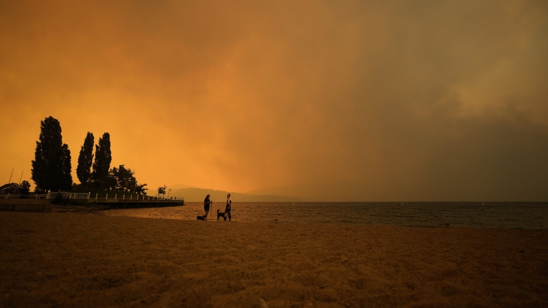 Smoke from the McDougall Creek wildfire fills the air and nearly blocks out the sun as people take in the view of Okanagan Lake from Tugboat Beach, in Kelowna, B.C., Friday, Aug. 18, 2023. THE CANADIAN PRESS/Darryl Dyck