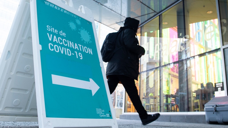 A man walks by a COVID-19 vaccination sign in Montreal, Thursday, December 23, 2021, as the COVID-19 pandemic continues in Canada and around the world. THE CANADIAN PRESS/Graham Hughes