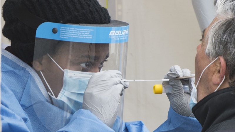 A health-care worker prepares to swab a man at a walk-in COVID-19 test clinic in Montreal North, Sunday, May 10, 2020. (Graham Hughes/The Canadian Press)