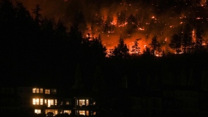 The McDougall Creek wildfire burns on the mountainside above a home in West Kelowna, B.C., on Aug. 18, 2023. (THE CANADIAN PRESS/Darryl Dyck)