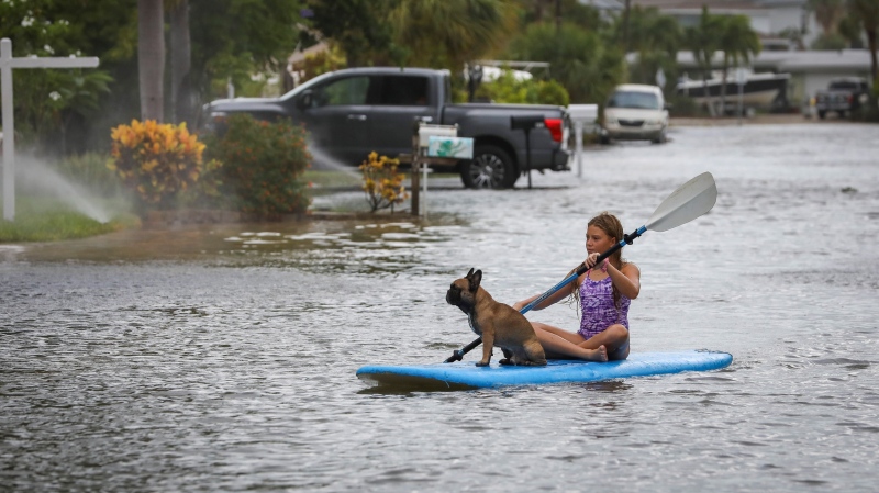 Lily Gumos, 11, of St. Pete Beach, kayaks with her French bulldog along Blind Pass Road and 86th Avenue Wednesday, Aug. 30, 2023 in St. Pete Beach, Fla. (Chris Urso/Tampa Bay Times via AP)