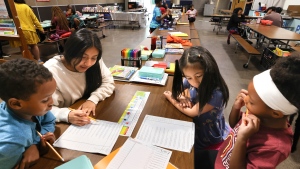 Ayub Mohamed, left, 7 years, gets help from Esmeralda Jimenez, 13, left back, volunteer tutor; while Olivia Elaydo, 7, right back, and Eden Pollard, 6, right, work on math problems during a summer tutoring program with School Connect WA at Dearborn Park International Elementary School in Seattle on Friday, July 28, 2023. (Karen Ducey/The Seattle Times via AP)