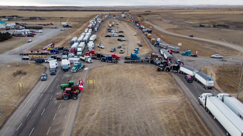 Anti-mandate demonstrators gather as a truck convoy blocks the highway the busy U.S. border crossing in Coutts, Alta., Monday, Jan. 31, 2022. THE CANADIAN PRESS/Jeff McIntosh 