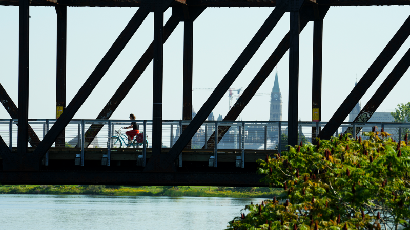 The Peace Tower of Parliament Hill is seen in the distance as a cyclist makes their way over the finished Chief William Command Bridge multi-use pathway over the Ottawa River in Ottawa on Wednesday, Aug. 23, 2023. The newly finish recreational corridor links Ottawa and Gatineau, Quebec. THE CANADIAN PRESS/Sean Kilpatrick