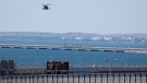 A Russian military helicopter flies over damaged parts of an automobile link of the Crimean Bridge connecting Russian mainland and Crimean peninsula over the Kerch Strait not far from Kerch, Crimea, on Monday, July 17, 2023. Russia said Saturday its forces destroyed three Ukrainian naval drones being used in an attempt to attack the brige, forcing its temporary closure for a third time in less than a year. (AP Photo)