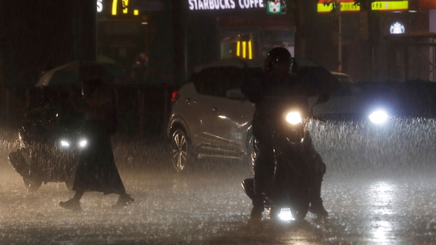 People walk and drive under heavy rain as the Typhoon Haikui approaches the country, in Taipei, Taiwan, Saturday, Sept. 2, 2023. (AP Photo/Chiang Ying-ying)