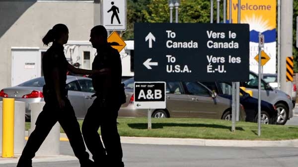 Canadian border guards are silhouetted as they replace each other at an inspection booth at the Douglas border crossing on the Canada-USA border in Surrey, B.C., on Thursday August 20, 2009. (Darryl Dyck / THE CANADIAN PRESS)
