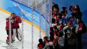 Canada's Emily Clark (26) and Canada goalkeeper Emerance Maschmeyer (38) pose in front of Olympic workers after defeating United States in the women's gold medal hockey game at the 2022 Winter Olympics, Thursday, Feb. 17, 2022, in Beijing. (AP Photo/Jae C. Hong)