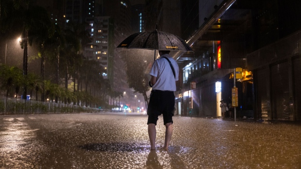 A pedestrian waits for a bus on a flooded street following heavy rainstorms in Hong Kong, Friday, Sept. 8, 2023. (AP Photo/Louise Delmotte)
