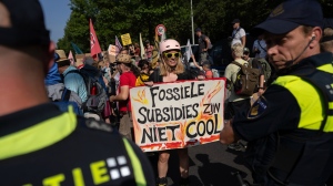 A protester holds a sign reading "Fossil Subsidies Are Not Cool" as they block a highway during a climate protest of Extinction Rebellion and other activists near the Dutch parliament in The Hague, Netherlands, Saturday, Sept. 9, 2023. (AP Photo/Peter Dejong)