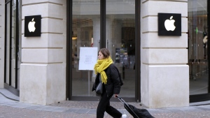 A woman walks past a closed Apple Store in Lille, northern France, Monday, March 16, 2020. (AP Photo/Michel Spingler, File)