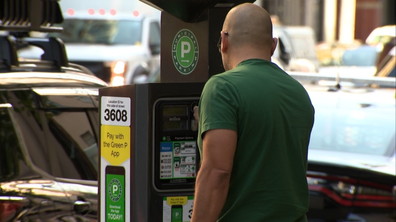 Someone paying for parking in Toronto using a parking machine. (CTV News Toronto)