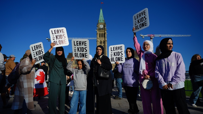 People hold signs during a demonstration on Parliament Hill in Ottawa on Wednesday, Sept. 20, 2023.  THE CANADIAN PRESS/Sean Kilpatrick