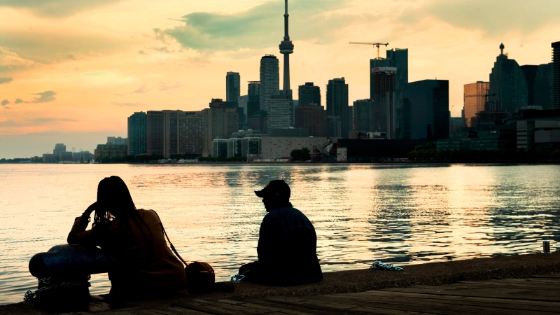 In this file photo, two people sit and watch storm clouds passing by the skyline in Toronto on Tuesday, June 8, 2021. THE CANADIAN PRESS/Frank Gunn