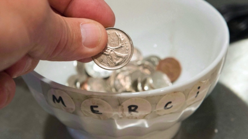FILE - A customer drops a coin in a tip jar at a sandwich shop Tuesday, November 13, 2012 in Montreal. (THE CANADIAN PRESS/Ryan Remiorz, File)
