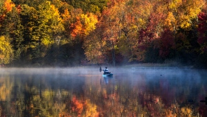 A fisherman in a kayak on Bass Lake is framed by fall colours in central Ontario, Monday, October 10, 2022. (THE CANADIAN PRESS/Fred Thornhill)