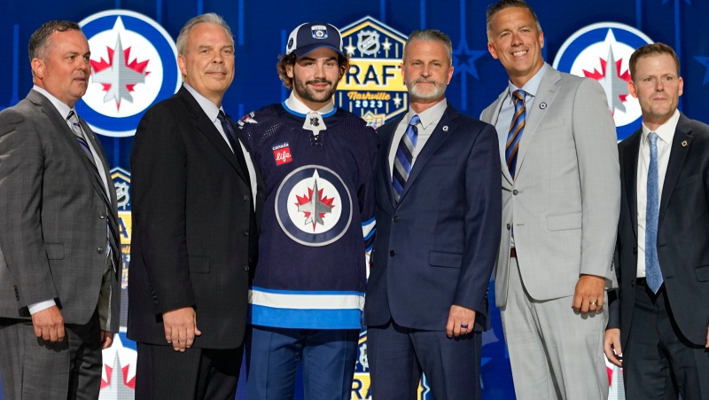 Colby Barlow, center left, poses with Winnipeg Jets officials after being picked by the team during the first round of the NHL hockey draft Wednesday, June 28, 2023, in Nashville, Tenn. (AP Photo/George Walker IV)