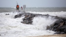 Waves break along the jetty at Rudee Inlet in Virginia Beach, Va., on Friday, Sept. 22, 2023, as Tropical Storm Ophelia approaches the area. (Kendall Warner/The Virginian-Pilot via AP)