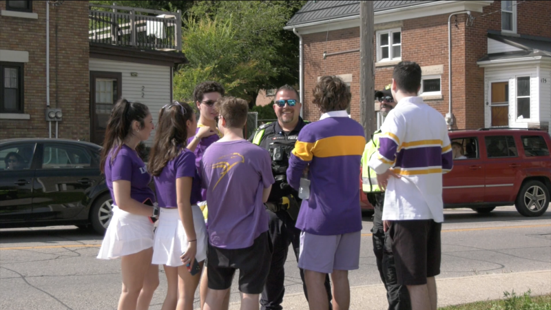 A group of students chat with a police officer during homecoming weekend 2023 in Waterloo. (Hannah Schmidt/CTV News)