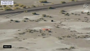 This image taken from video provided by NASA TV shows the capsule released by the Osiris-Rex spacecraft lying on the surface near the parachute after landing to Earth, Sunday Sept. 24 2023. (NASA TV via AP)