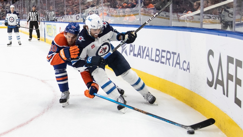 Winnipeg Jets' Alex Iafallo (9) and Edmonton Oilers' Brandon Sutter (20) battle for the puck during first period NHL preseason action in Edmonton on Sunday September 24, 2023. (THE CANADIAN PRESS/Jason Franson)
