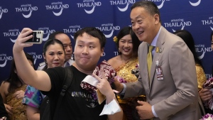 Chinese tourists takes selfies with Thailand's Prime Minister Srettha Thavisin, right, on their arrivals at Suvarnabhumi International Airport in Samut Prakarn province, Thailand, Monday, Sept. 25, 2023. (AP Photo/Sakchai Lalit)